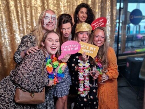 photobooth-trouwfeest-fotoprops Groep vriendinnen met kleurrijke props en feestaccessoires poseert vrolijk voor een photobooth op een trouwfeest. De fotobooth zorgt voor hilarische foto's en veel interactie tijdens de bruiloft.