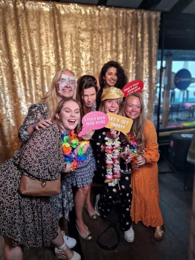 Groep vriendinnen met kleurrijke props en feestaccessoires poseert vrolijk voor een photobooth op een trouwfeest. De fotobooth zorgt voor hilarische foto's en veel interactie tijdens de bruiloft.